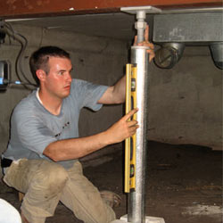 A contractor in Simpsonville installing a crawl space jack post.