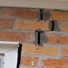 A brick wall displaying stair-step cracks and messy tuckpointing on a Columbia home