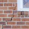 long jagged cracks starting at the corner of a window along a brick wall on a Inman home
