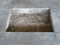 Creating the hole in the garage slab floor during the wall anchor installation in Brevard.
