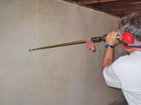 Drilling the hole in the foundation wall for street creep repairs in Piedmont