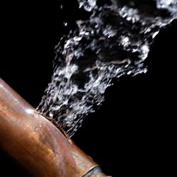 A bursting copper pipe in Columbia, with water gushing out.