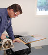 installing a waterproof vapor barrier on a basement floor to prepare for basement carpeting in a Columbia home